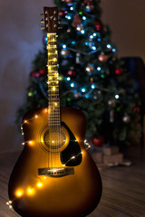 Guitar with Christmas lights with a soft focused decorated Christmas Tree in the background