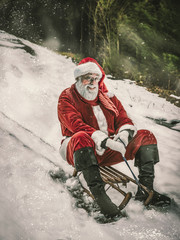 Happy Christmas holiday. Cheerful Santa Claus sledding fun riding down a hill in a snowy forest. Active lifestyle concept.