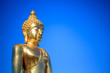 Fototapeta na wymiar Big golden buddha statue sitting on blue sky background.