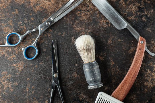 vintage barber tools dangerous razor hairdressing scissors old manual clipper comb shaving brush. Beautiful rusty metal background.