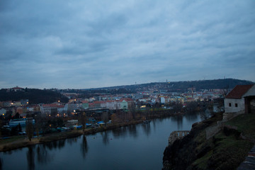 Fototapeta na wymiar Winter panorama from Vysehrad Castle to the evening city of Prague, residential areas, the Vltava River, moorings with boats and boats and city transport.