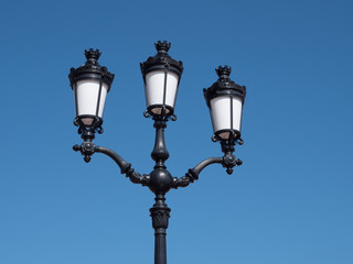 Straßenlaterne mit drei Lampen vor blauem Himmel