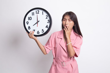 Sleepy young Asian woman with a clock in the morning.