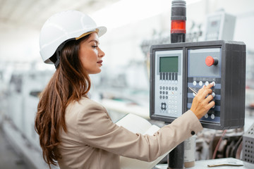 Portrait of businesswoman in factory. Young female architect with helmet in suit.	