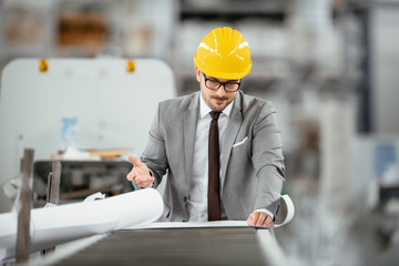 Businessman in warehouse. Young architect with helmet in suit. 