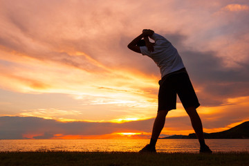 Young sports man doing stretching after run at the beach