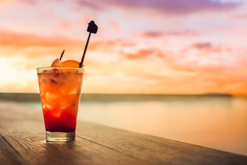 Mocktail on the table near swimming pool and sunset cloud.