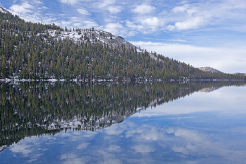 Tenaya Lake with reflections of the Sierra Nevada Mountains and conifers in calm water, Yosemite National Park, California, USA 