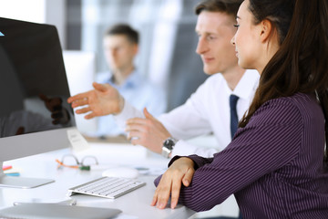 Business woman and man discussing questions while using computer at workplace in modern office....