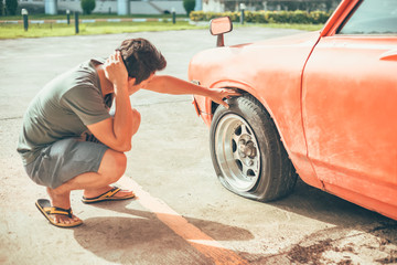 A man headache when car breakdown and wheel flat tire in parking