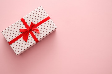 Gift with a red ribbon on a pink background. Concept for the holiday.