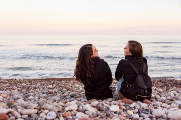 couple of lesbian girls sitting on the beach watching and enjoying a beautiful sunset together