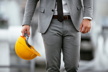Close up of businessman in suit holding helmet. 