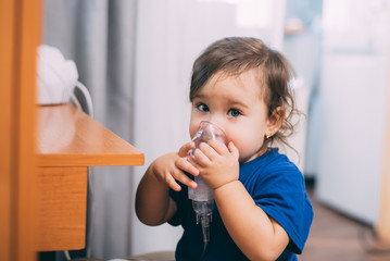 a little girl yourself holding the mask of the nebulizer, making inhalation