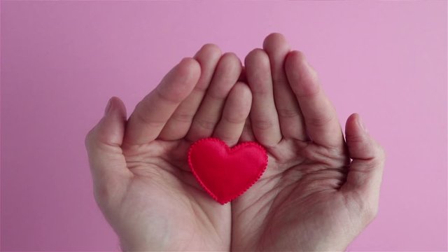 man hand holding red heart shape in hands close up happy valentines day health care concept