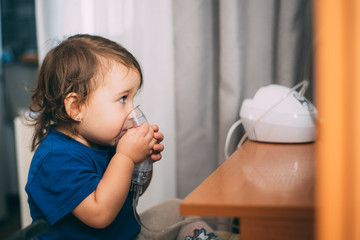 a little girl yourself holding the mask of the nebulizer, making inhalation