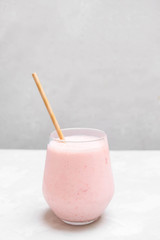 Glass cup of indian drink Strawberry Lassi on grey background