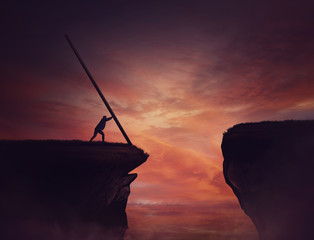 Businessman pushing a long beam, creating an improvised bridge to cross the abyss obstacle. Cover the gap and reach other side of the cliff. Mission accomplishment, overcome and success concept. - obrazy, fototapety, plakaty