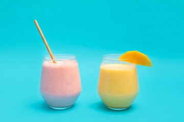 Traditional indian Mango Lassi and Strawberry Lassi drinks in glass cups on blue background