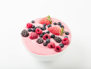 Smoothie bowl with yogurt, muesli and frozen berry. Pink yogurt smoothie bowl topped with frozen berries raspberries, strawberries, blackberries and blueberries. Healthy summer dessert. 