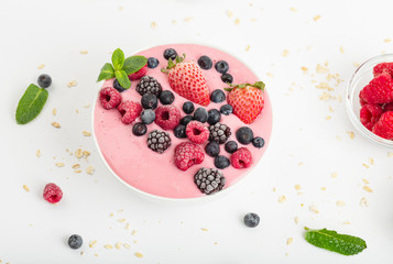 Smoothie bowl with yogurt, muesli and frozen berry. Pink yogurt smoothie bowl topped with frozen berries raspberries, strawberries, blackberries and blueberries. Healthy summer dessert. 