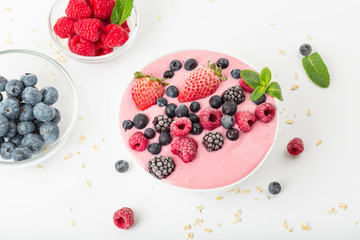 Smoothie bowl with yogurt, muesli and frozen berry. Pink yogurt smoothie bowl topped with frozen berries raspberries, strawberries, blackberries and blueberries. Healthy summer dessert. 