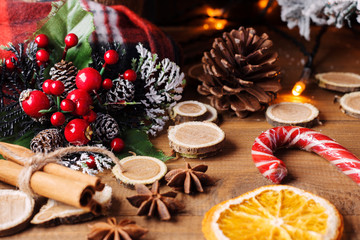 Christmas, New Year background greeting card banner. Christmas branch on a wooden background next to slices of orange, spicy spices and a frozen cane. Selective focus. Copy space