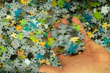 Obraz na płótnie Canvas puzzles pattern of randomly mixed puzzle pieces and with the hand with which different puzzle pieces fall, in blurry motion