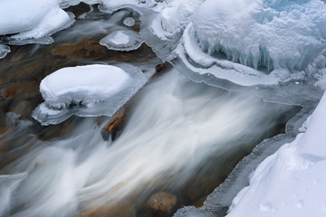 Winter landscape of cascade captured with motion blur and framed by blue ice, Gull Creek, Michigan, USA