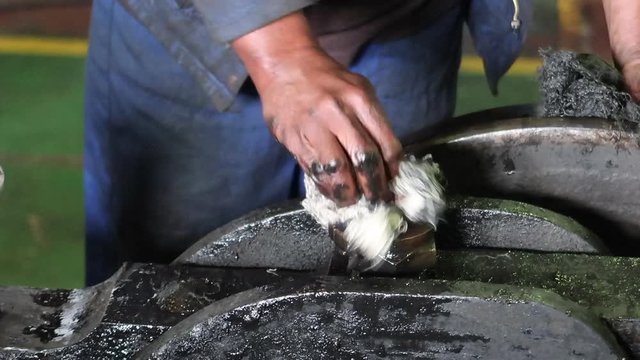 Man scrubs grime and grease off hatch on heavy duty industrial equipment, closeup