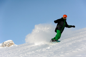 Snowboarder slides on mountain and raises up snow