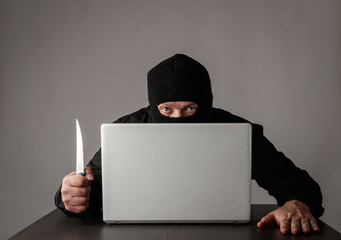 Hacker in mask using a laptop.