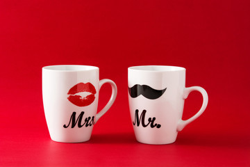 Mugs with moustache and lips for Valentine's Day on red background