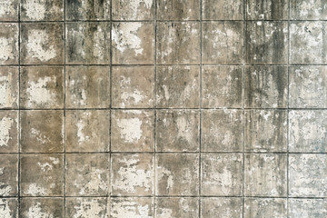 Old, weathered, dirty, stucco pealed, aged outdoor gray cement / concrete wall, with cracks and scratches, of abandoned industrial building with square grid lines in retro grungy style.