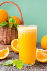 A glass of freshly squeezed juice surrounded by fresh oranges and tangerines. Vertical photo.