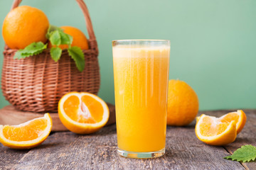 Naklejka na ściany i meble A glass of freshly squeezed juice surrounded by fresh oranges and tangerines. Horizontal photo.