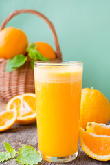 A glass of freshly squeezed juice surrounded by fresh oranges and tangerines. Vertical photo.