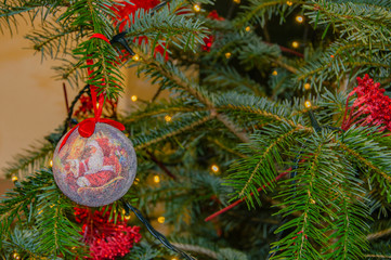 Red ball with Santa Claus and Decorated Christmas tree closeup. Fairy lights.