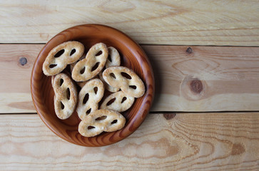 Flat lay view of a wooden bowl filled with 'krakeling' a very popular sort of Dutch cookie. Wooden table background and copy space to the right.