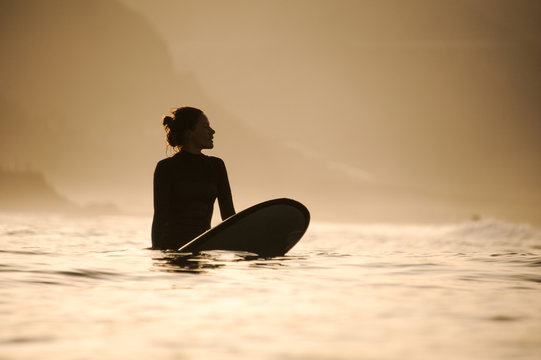 Silhouette of a surfer girl in the waters