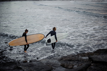 Man and woman with surfboards going to water