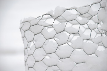 Close up of snow covered chicken wire fence