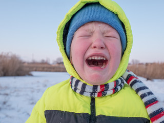 Charming Little boy crying because he fell in snow, riding sled. Outdoor activities on winter day. Casual fashion for boy. Holidays in village