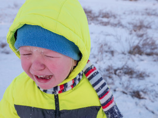Charming Little boy crying because he fell in snow, riding sled. Outdoor activities on winter day. Casual fashion for boy. Holidays in village