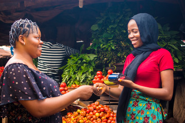 close up of an african woman selling food stuff in a local african market holding a mobile point of...