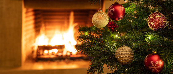 Christmas tree close up on burning fireplace background