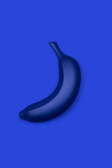 Dark blue banana on blue. Flat lay style. Monochrome trendy photo ispired by color of the year 2020