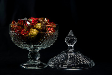 Obraz premium carved glass bonbonniere full of chocolates wrapped in red