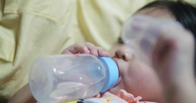 4k Ressolution Asain Baby Girl Lying On A Sofa And Drinking A Water From Bottle In A Living Room At Home.