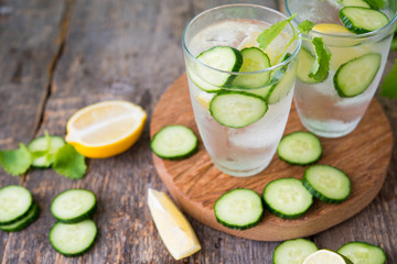 Refreshing detox water with cucumber, lemon and fresh mint on the wooden  background. Organic, vegan beverage.